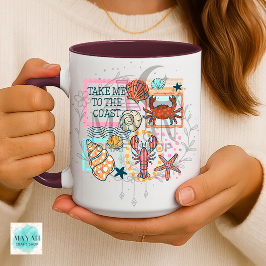 Person holding a mug with coastal design and text 'Take me to the coast'.