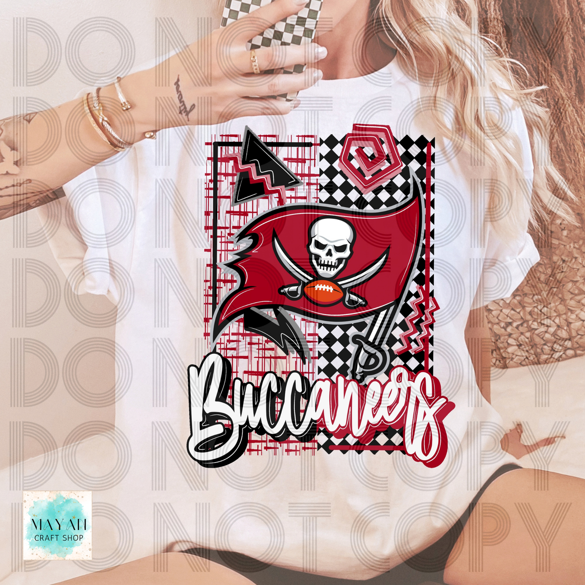 A woman wearing a white graphic T-shirt featuring the Tampa Bay football logo with a skull, football, and a word in script. The shirt has a large red, black, white, and gray graphic print on the front.