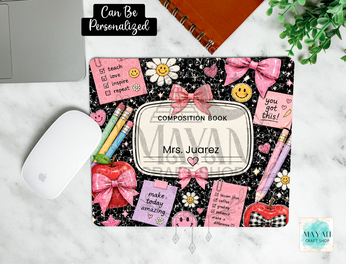 A personalized composition book mouse pad with a black glittery background, pink bows, daisies, and motivational quotes, shown on a marble desk with a white mouse, notebook, and plant.