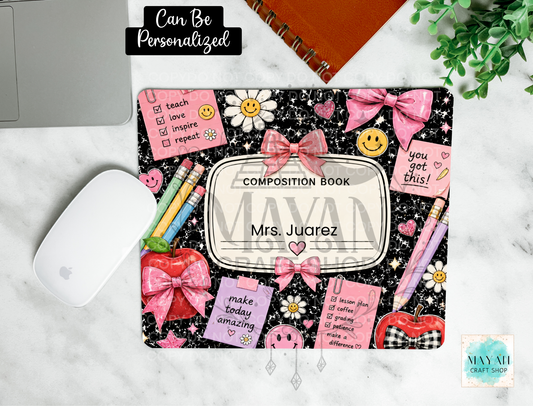 A personalized composition book mouse pad with a black glittery background, pink bows, daisies, and motivational quotes, shown on a marble desk with a white mouse, notebook, and plant.