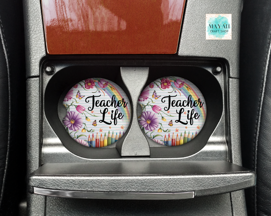 Two car coasters with 'Teacher Life' design in a holder on a car's cup holder.