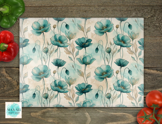 Cutting board with teal flowers on a wooden surface with vegetables.