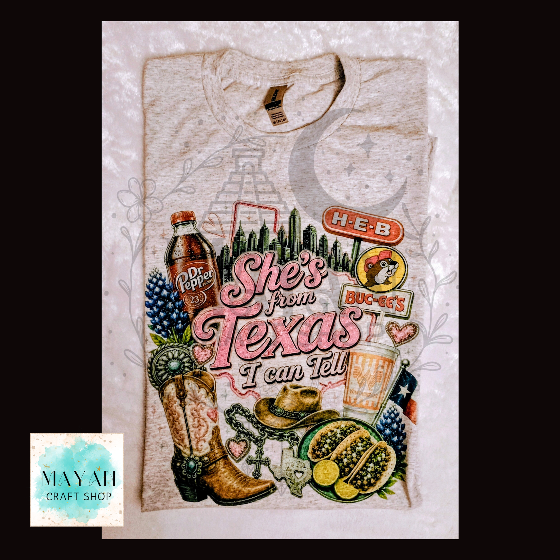 T-shirt with Texas-themed design featuring a boot, cowboy hat, and various Texas icons on a light gray background.