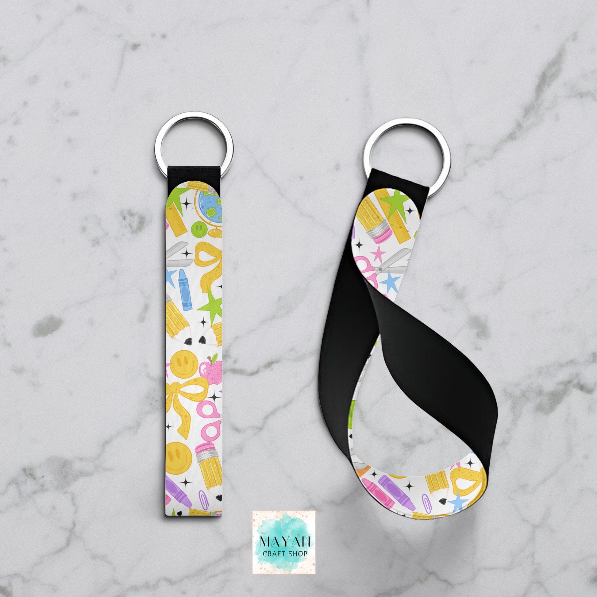 Two fabric keychains with silver metal key rings, displayed on a light gray marble background. One keychain is shown flat, and the other is twisted to display the strap's flexibility.