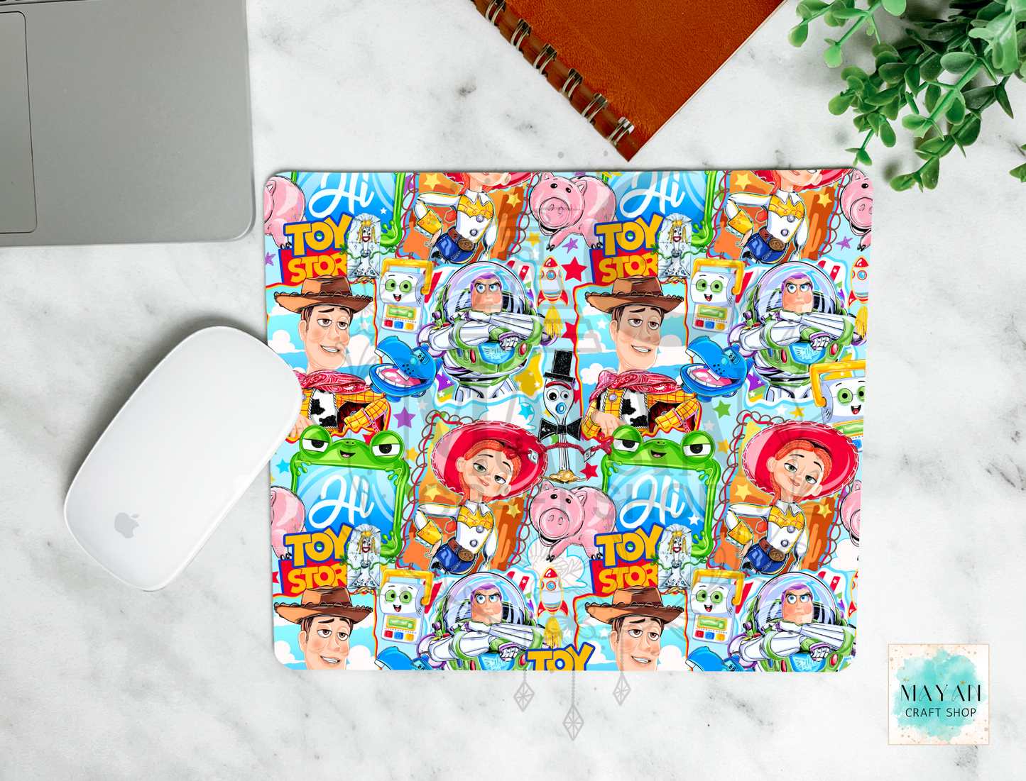Colorful with characters mouse pad on a marble surface with a laptop and plant.