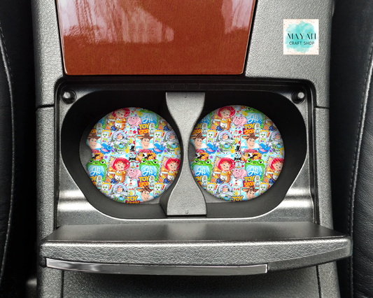 Two colorful car coasters with cartoon designs in a car cup holder.