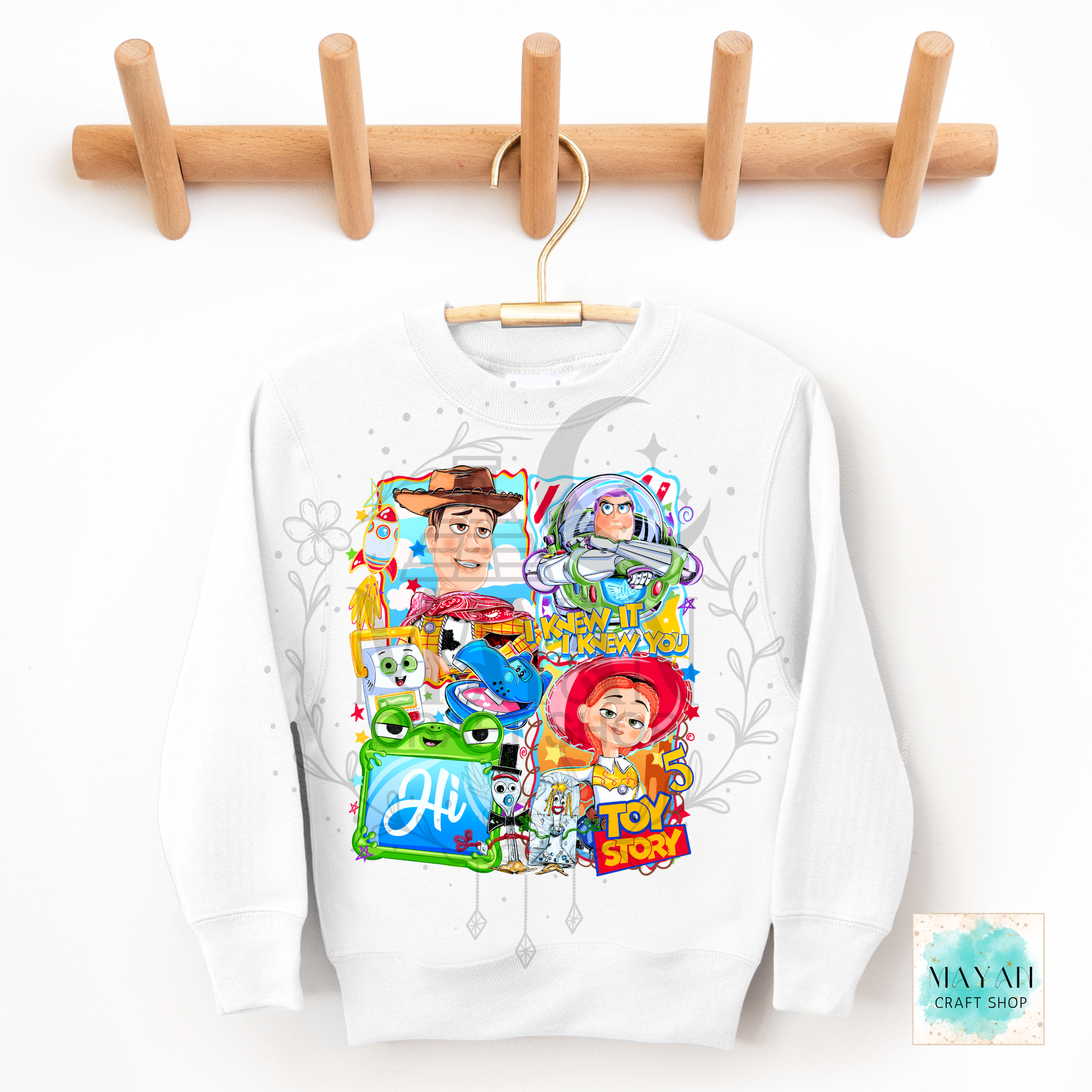 White sweatshirt with character graphics on a wooden hanger against a white background.