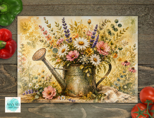 Cutting board of a watering can with flowers on a wooden surface.
