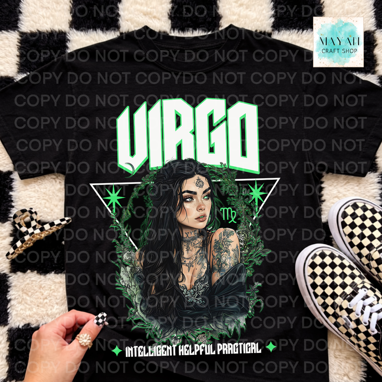 A black graphic t-shirt featuring a 'Virgo' zodiac design with a female illustration, green stars, and the text 'INTELLIGENT HELPFUL PRATICAL'. The shirt is displayed in a flat-lay arrangement on a black and white checkered rug, next to a hand, a small checkered accessory, and black-and-white checkered sneakers.