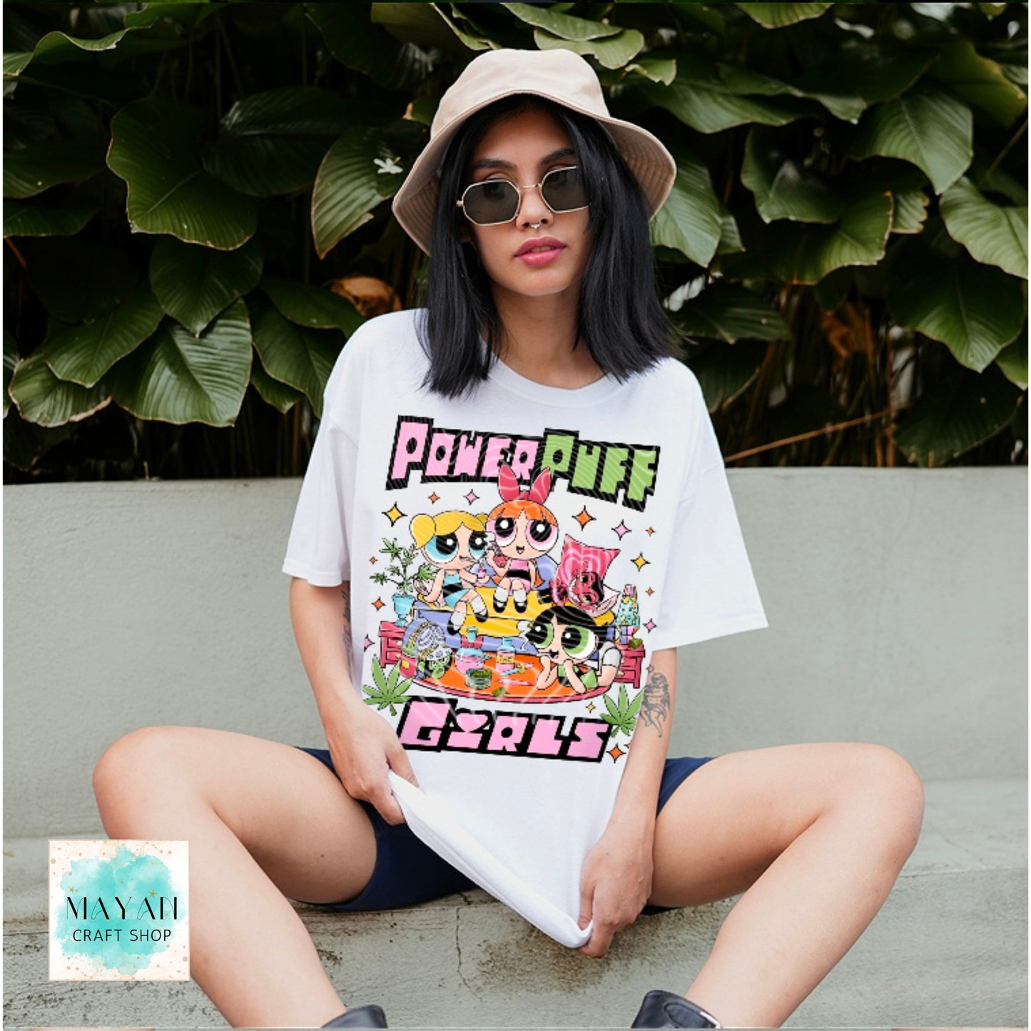 Person wearing a white t-shirt with a colorful design, sitting outdoors.