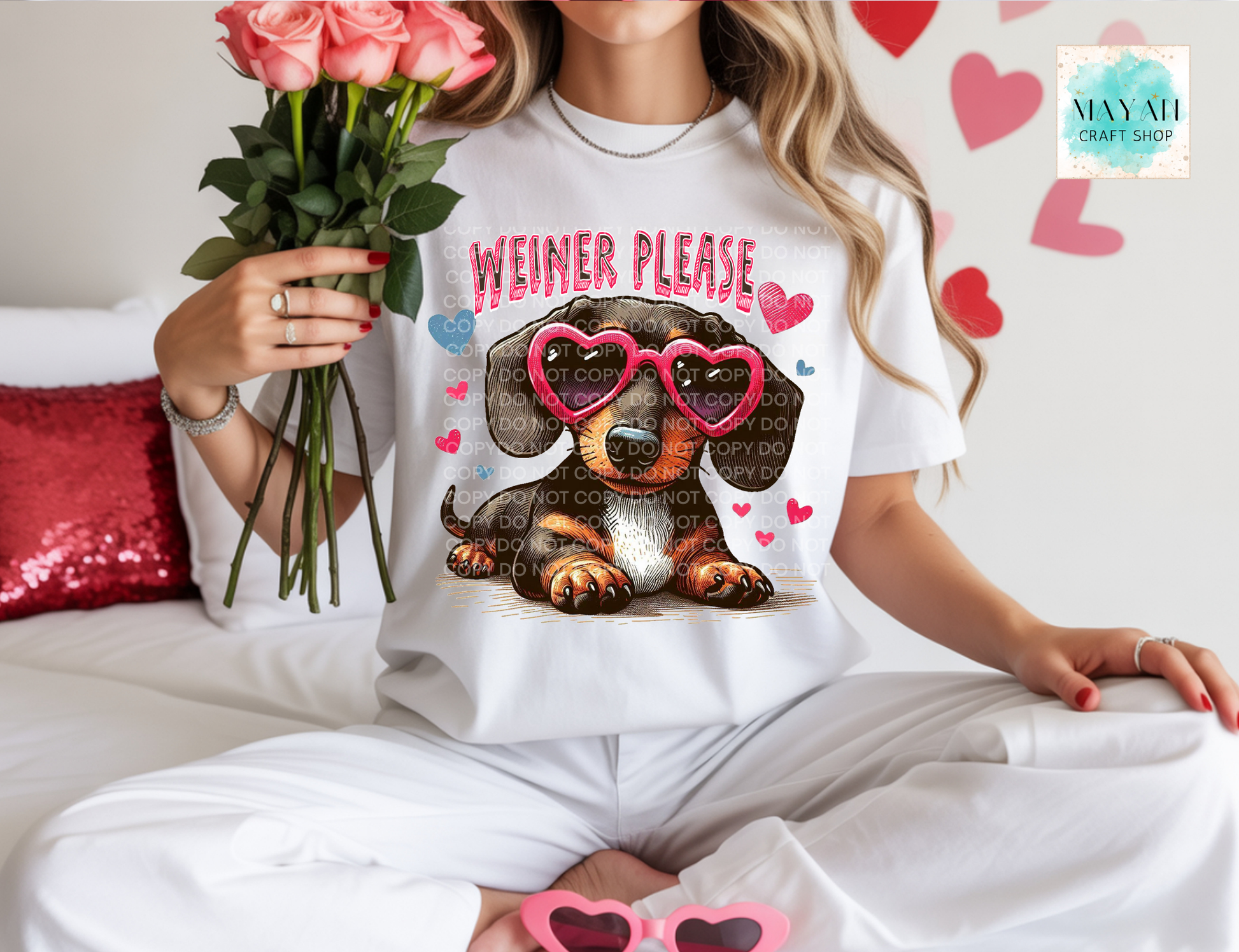Person wearing a t-shirt with a dachshund graphic and 'Weiner Please' text, holding flowers.