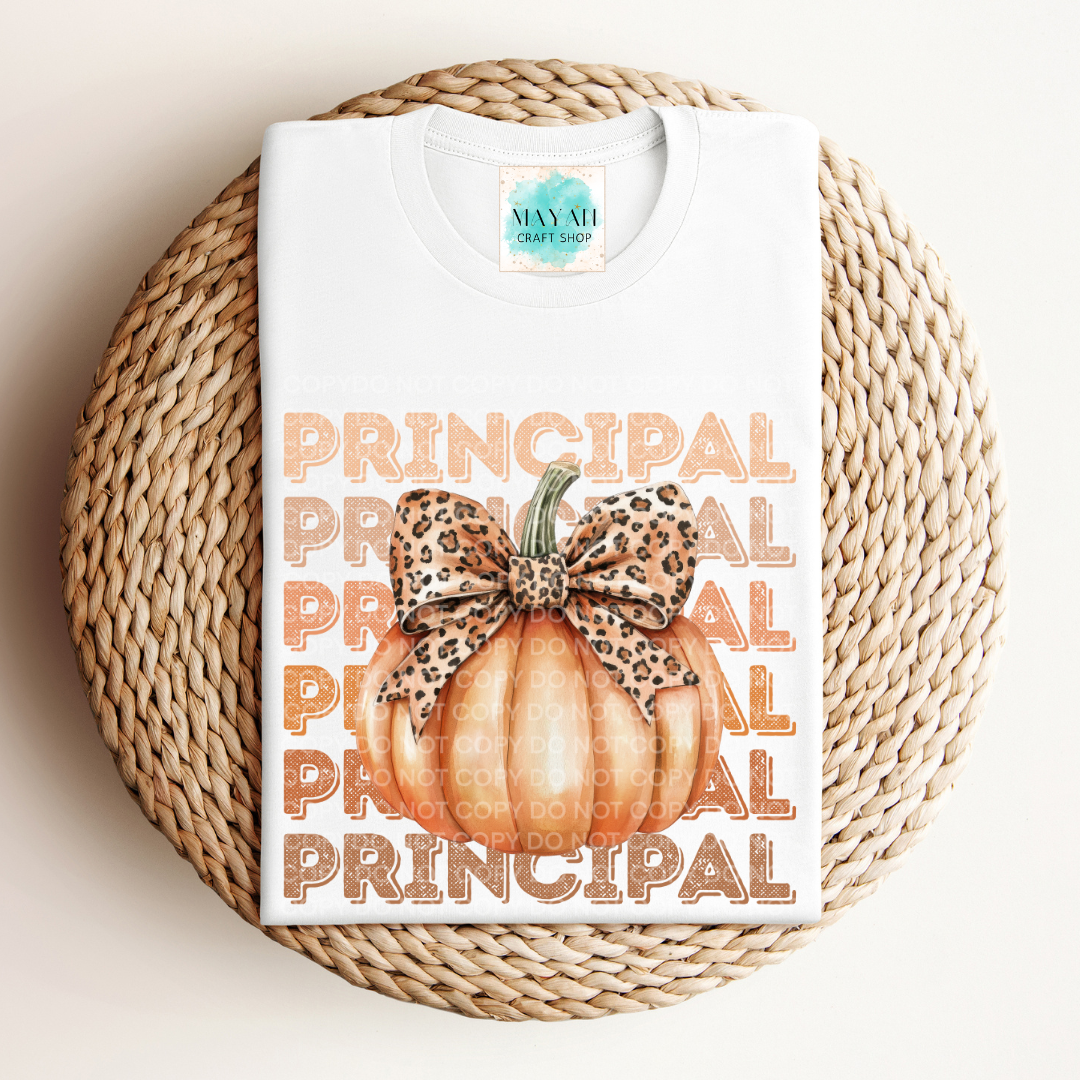 White t-shirt with 'Principal' text and pumpkin design on a woven mat