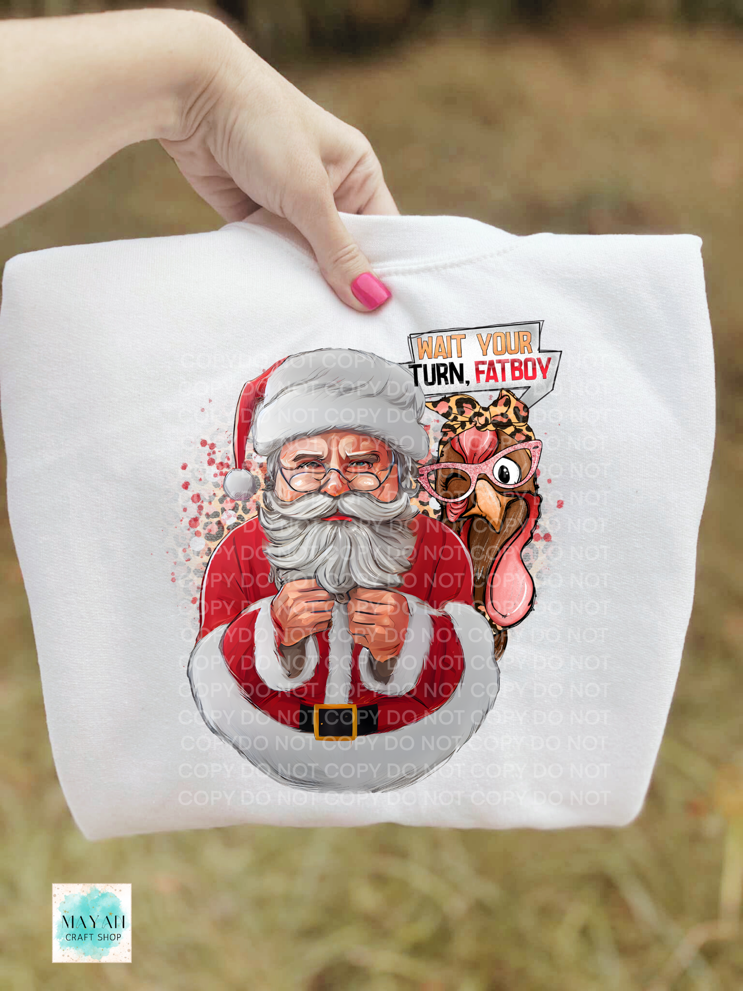 White sweatshirt with a printed design of Santa Claus and a turkey, held by a hand.