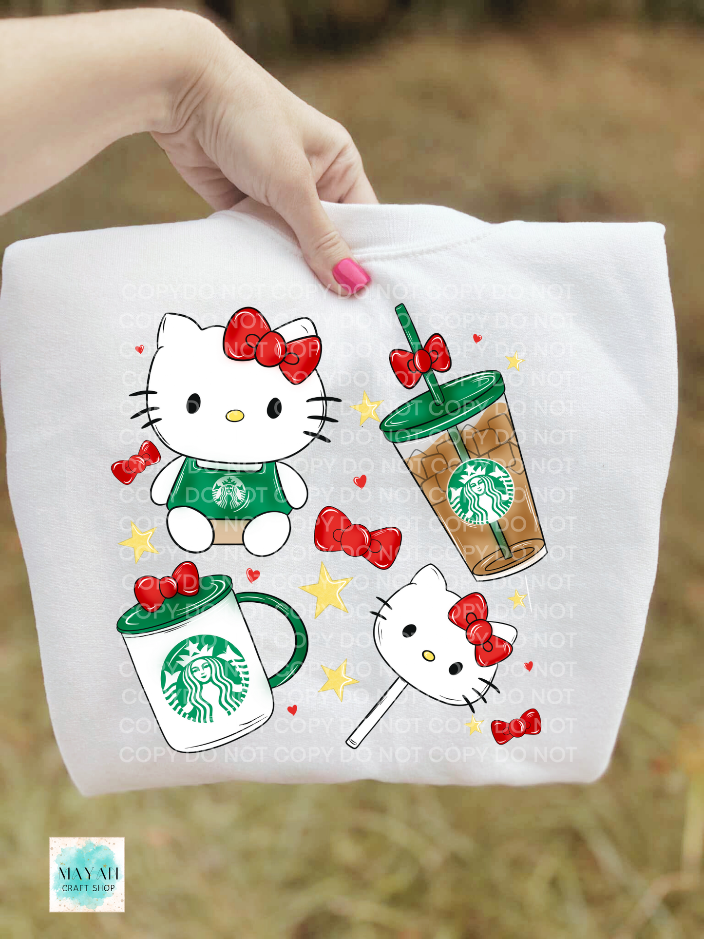 White sweatshirt with cat and coffee-themed designs held by a hand.