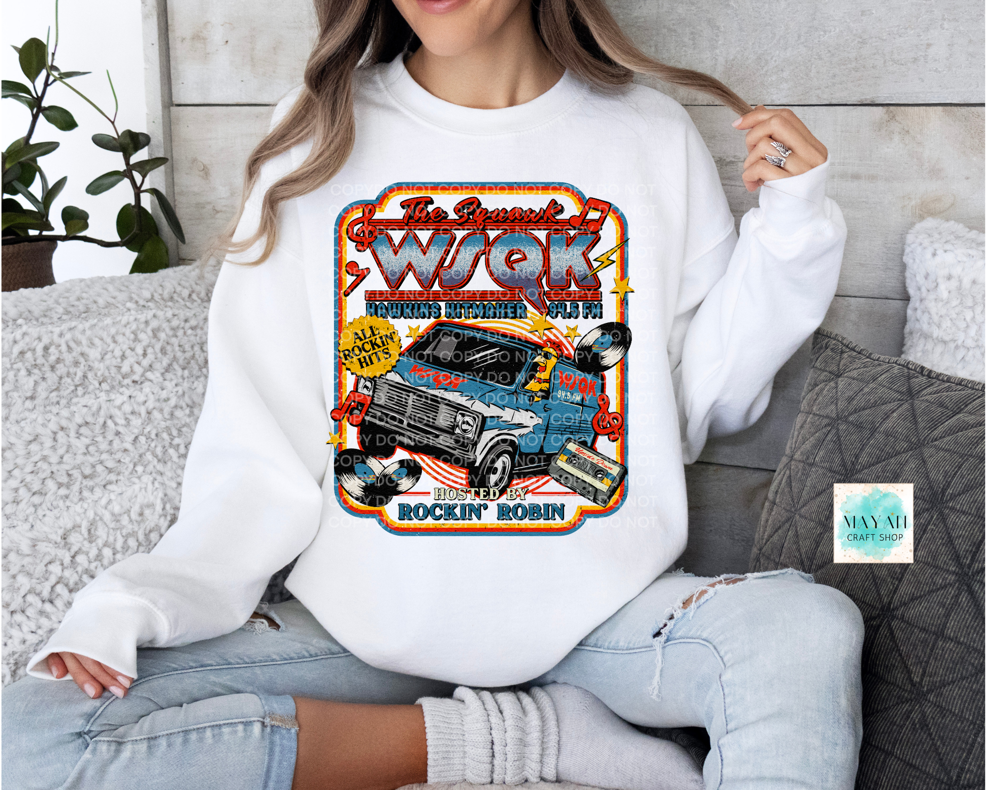 Person wearing a white sweatshirt with a graphic design of a truck and text.