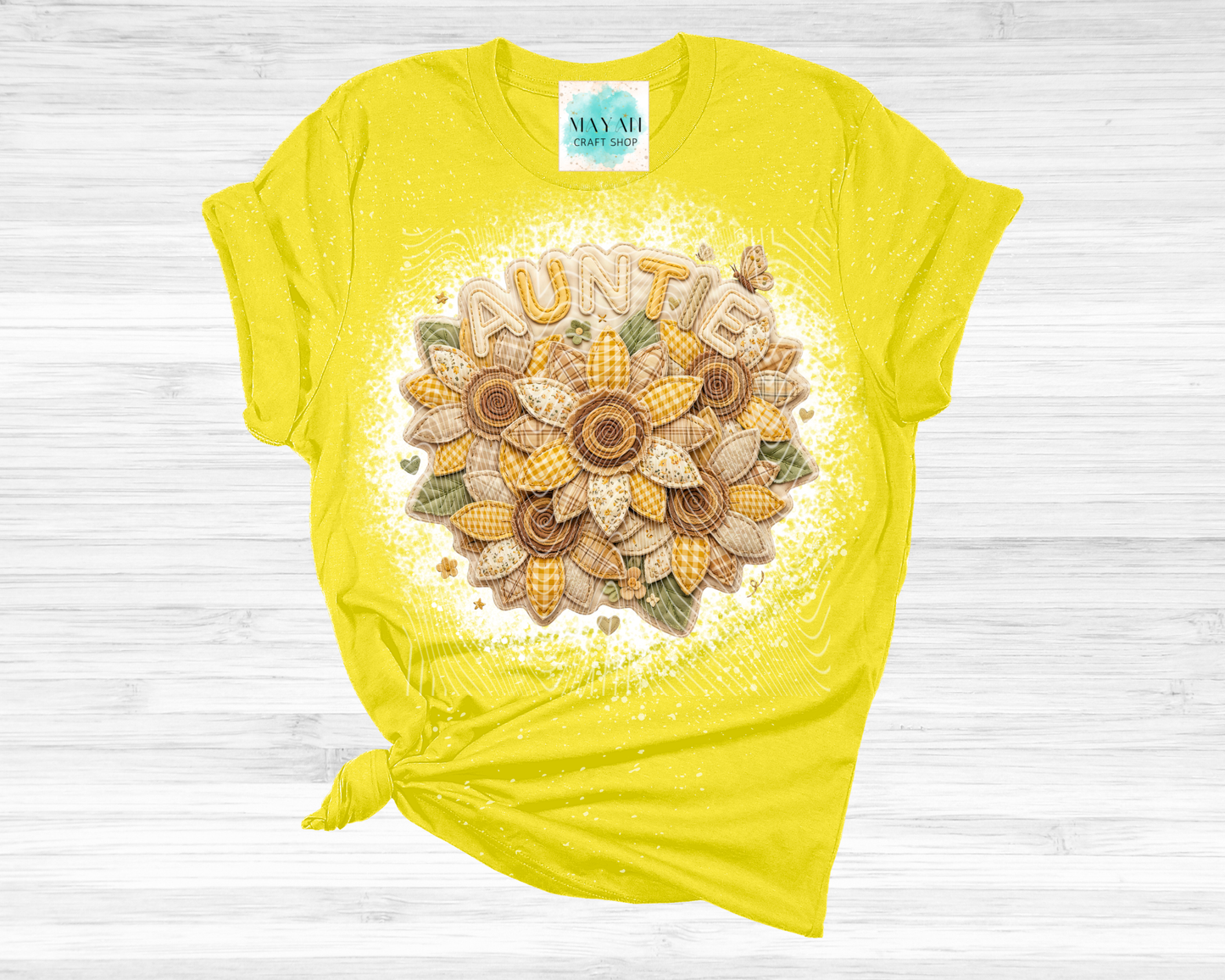 Yellow t-shirt with floral design and 'Auntie' text on a wooden surface