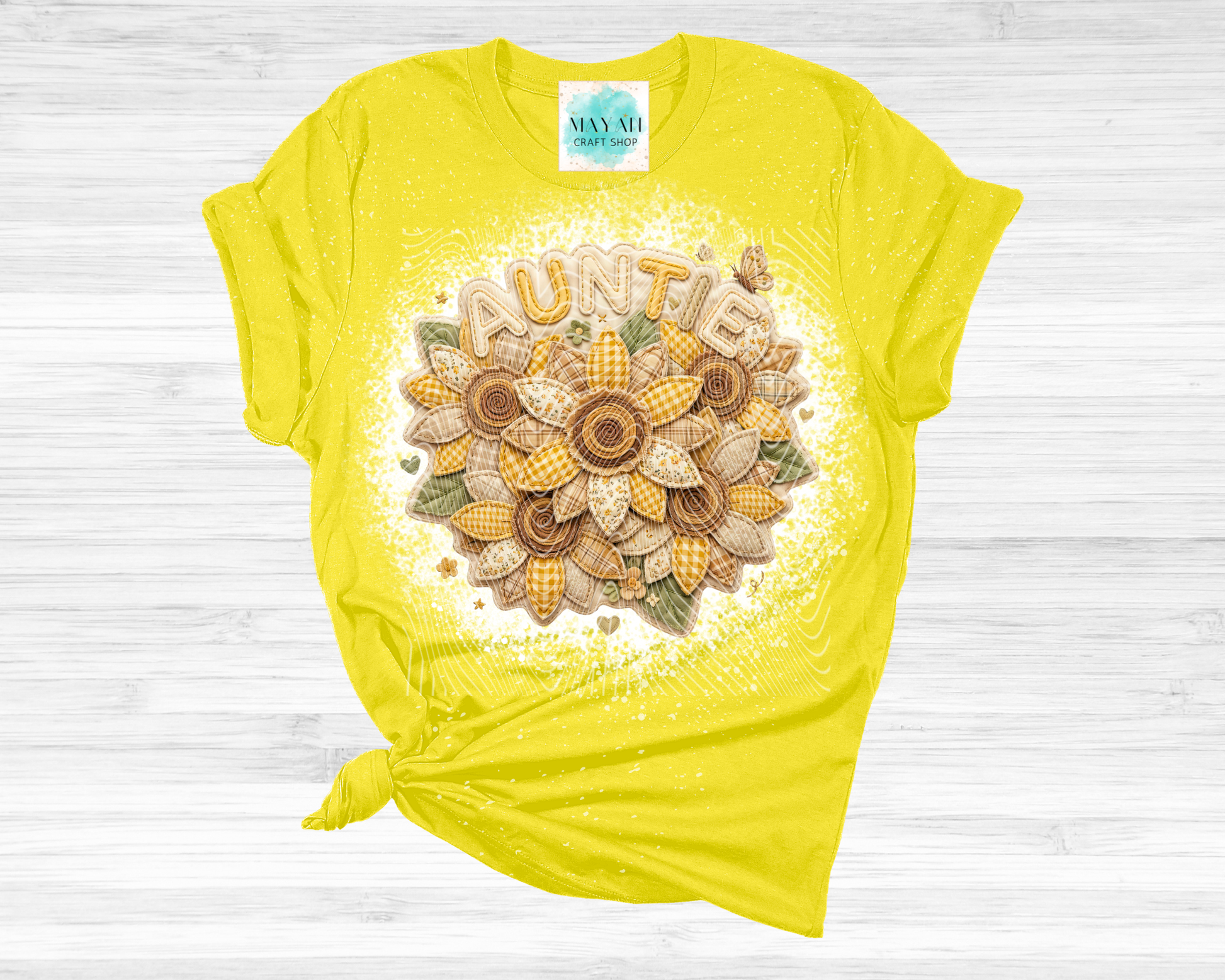 Yellow t-shirt with floral design and 'Auntie' text on a wooden surface