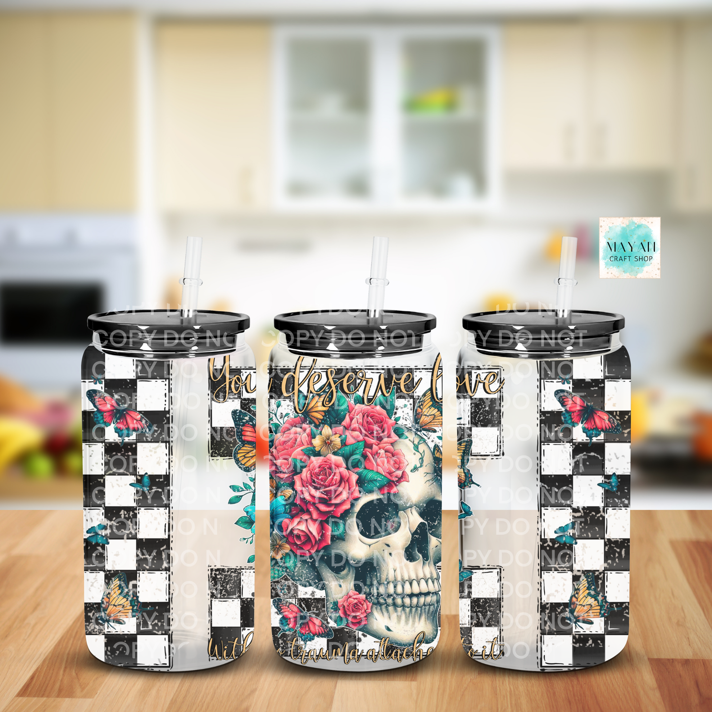 Three tumblers with floral and skull designs on a kitchen counter.