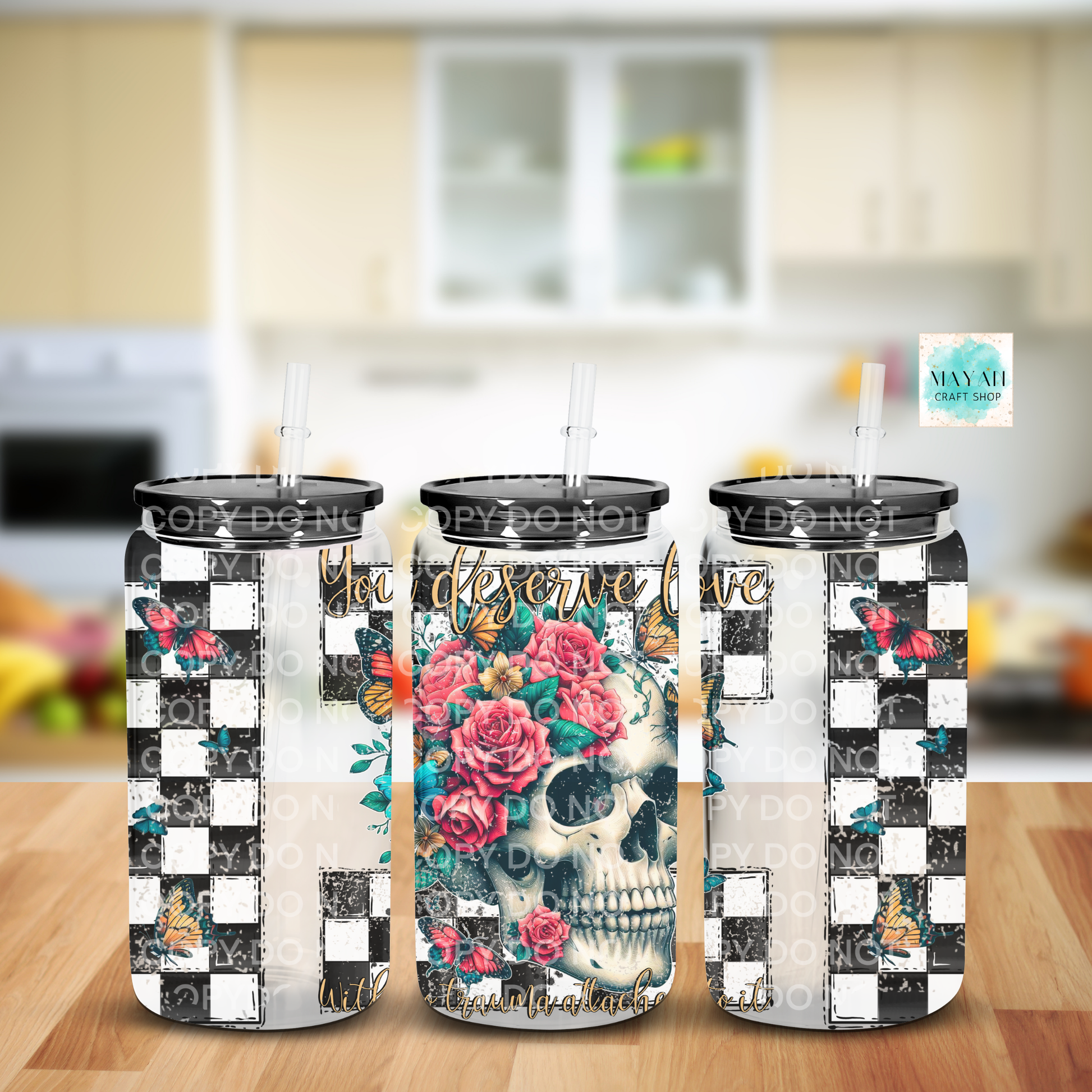 Three tumblers with floral and skull designs on a kitchen counter.