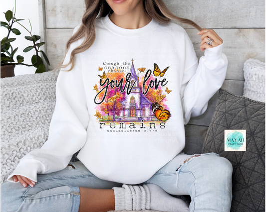 Person wearing a white sweatshirt with a colorful design and text, sitting on a couch.